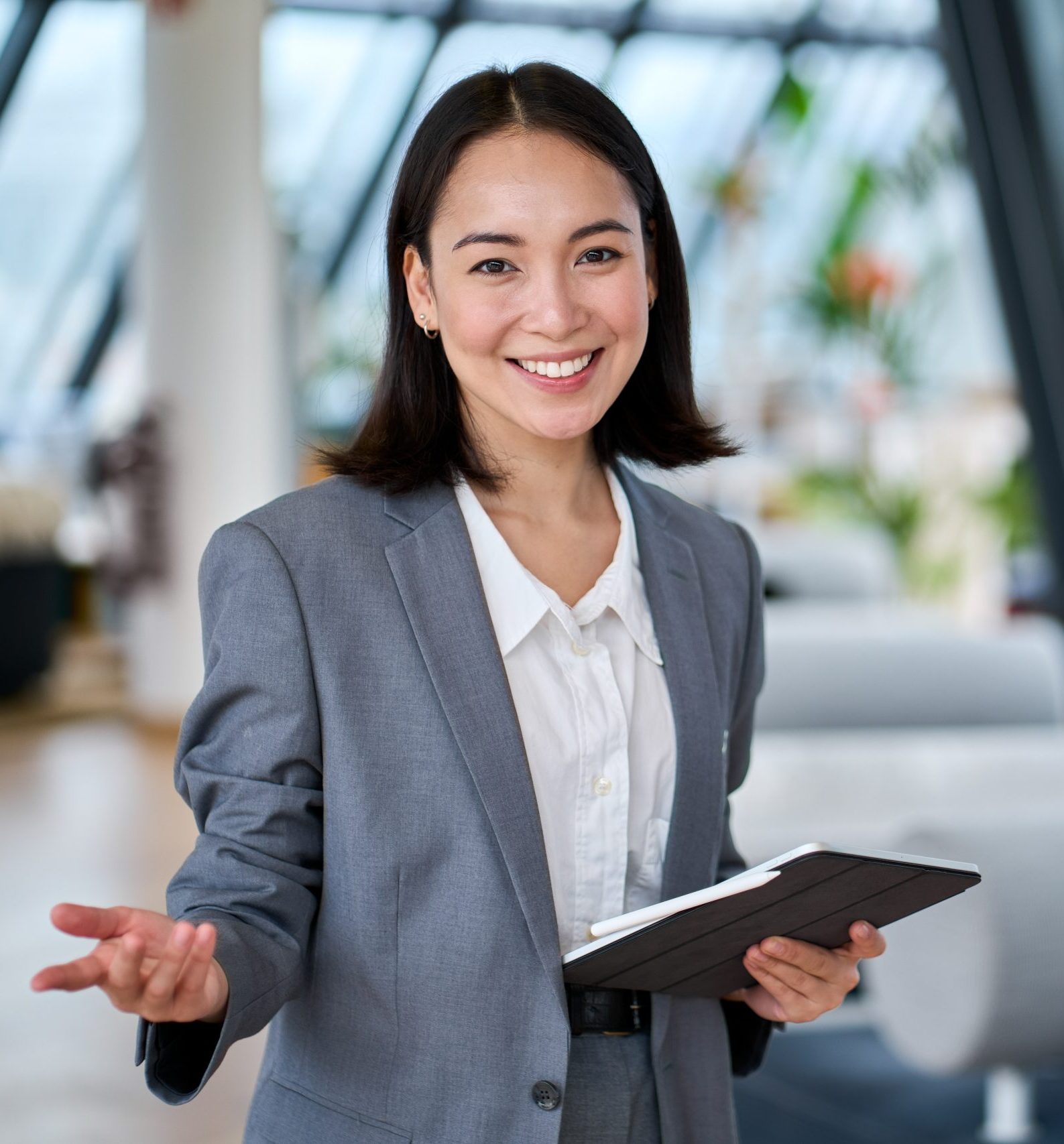 Cheerful young Asian saleswoman looking at camera welcoming client.